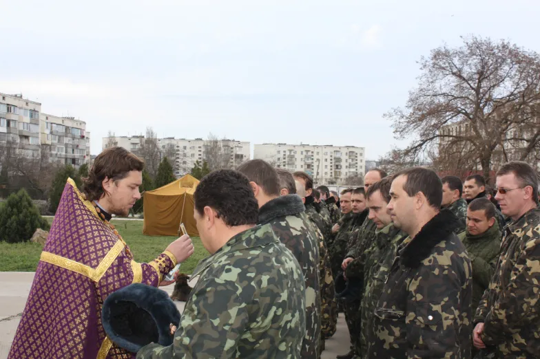 Baza Belbek na Krymie, żołnierze ukraińscy przyjmują komunię św. W tle osiedle bloków
